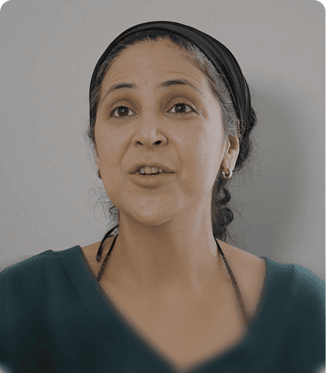 Erika, in a dark headband and green top, speaking to the camera
